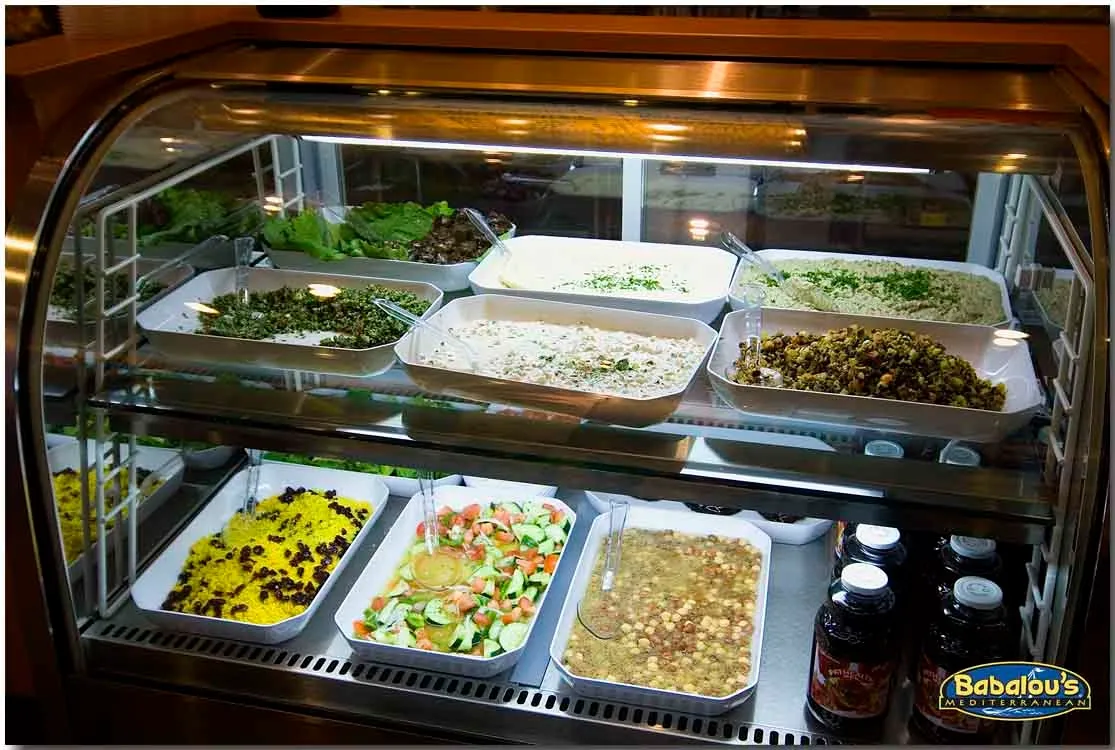 Display case filled with Mediterranean salads, rice, and daily trays